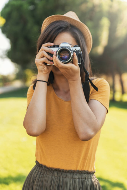 Young woman using a camera to take photo. - Фото, изображение