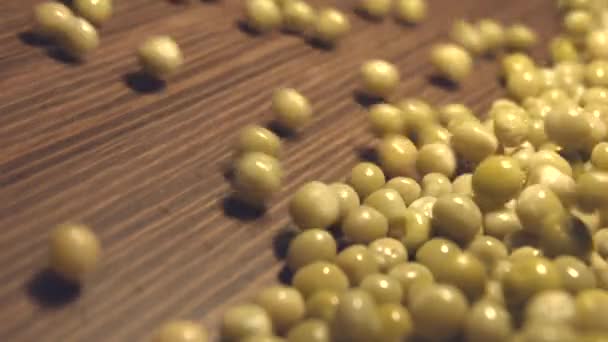 Canned green peas on a brown wooden background. 2 Shots. Slow motion. Vertical pan. Close-up.1. Canned green peas are rolling down ( from left to right ) on a brown wooden background and fills the all space frame.2. Vertical ( from bottom to top  - Materiał filmowy, wideo