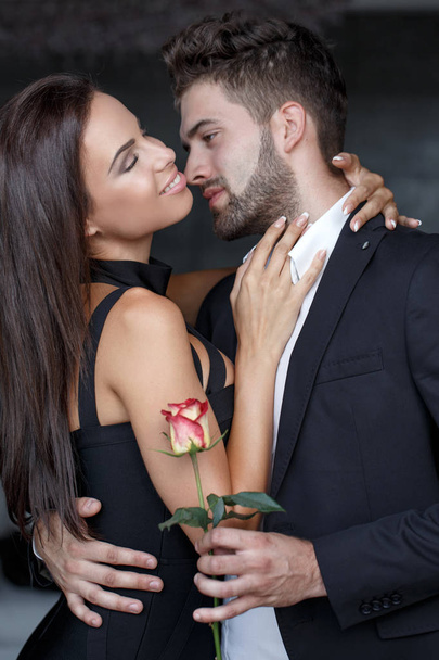 Νέος άνθρωπος Αγκαλιάζοντας γυναίκα και δίνουν τριαντάφυλλο - Φωτογραφία, εικόνα