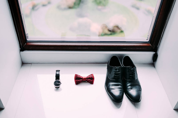 Grooms shoes, bow tie and watch on light window background - 写真・画像