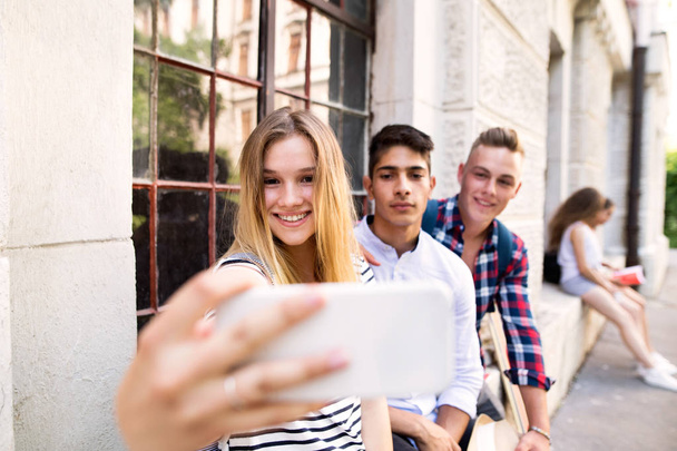 Group of students in front of university taking selfie. - 写真・画像