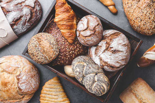 A basket full of delicious fresh bread on wooden background - Foto, imagen