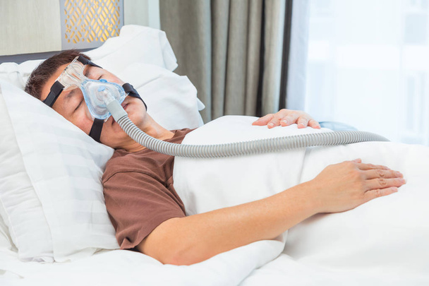 middle age asian man sleeping in his bed wearing CPAP mask conne - Photo, Image