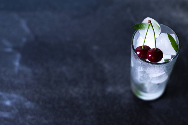 Natural ice in a glass with cherries on a black background. - Foto, immagini