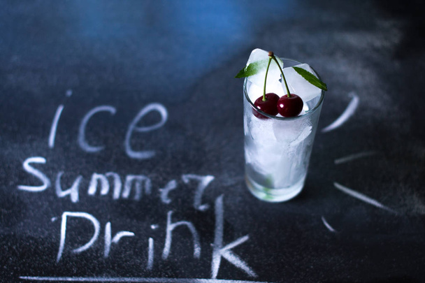 Natural ice in a glass with cherries on a black background. - Foto, afbeelding