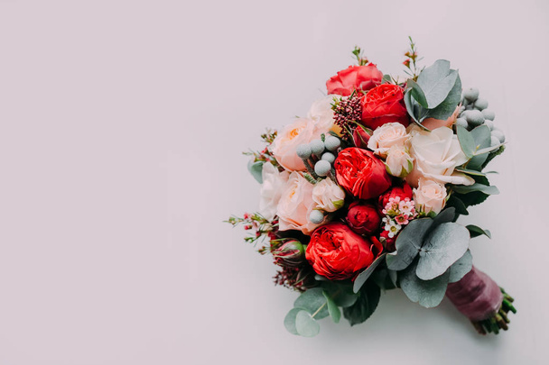 Wedding bouquet of red and cream roses on a light floor. Top view - 写真・画像