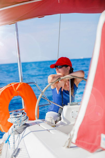 Girl captain on board of sailing yacht on summer cruise. Travel adventure, yachting with child on family vacation. - Foto, immagini
