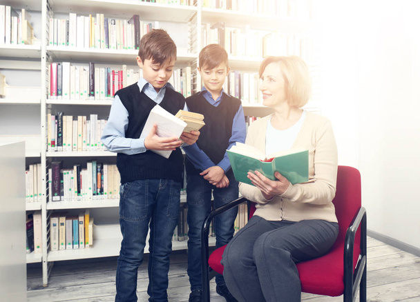 Teacher and little boys with books at school library - Fotoğraf, Görsel