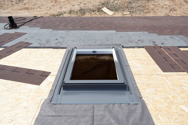 Installation eines Dachfensters auf einem Dach mit Asphaltschindeln oder Bitumenziegeln im Bau. - Foto, Bild