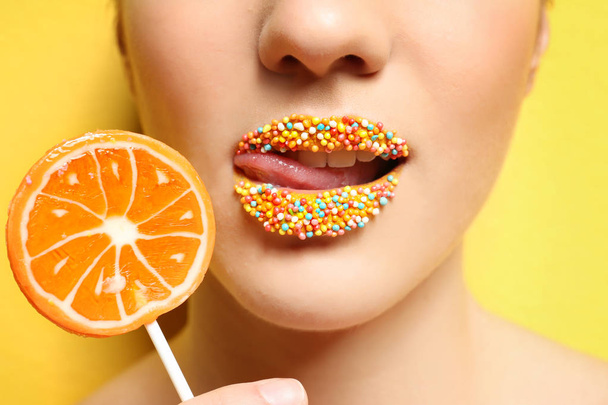 Beautiful young woman holding lollipop near lips  - Fotografie, Obrázek