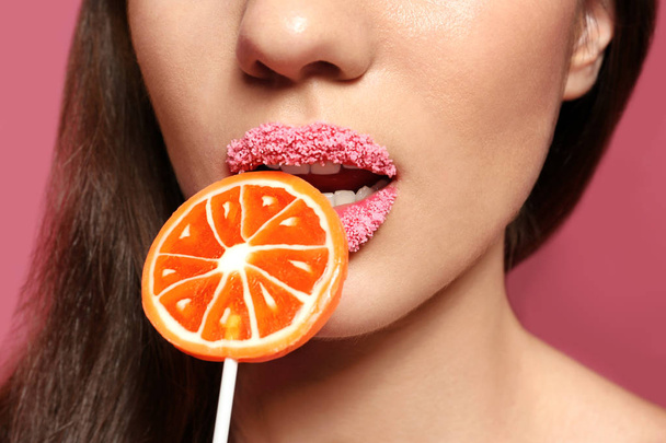 Beautiful young woman holding lollipop near lips  - Фото, изображение
