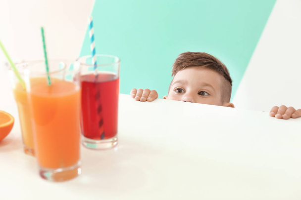 Cute little boy looking at glasses of juice  - Фото, изображение