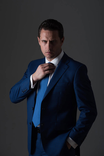 man adjusting tie in fashionable blue formal suit - Foto, afbeelding