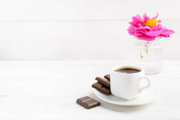 Cup of coffee with chocolate and flower on background over white table - Foto, Imagen