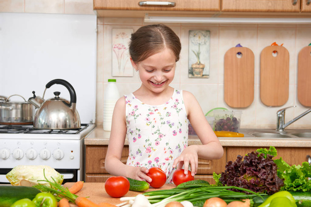 Child girl having fun with tomatoes. Home kitchen interior with fruits and vegetables. Healthy food concept - Zdjęcie, obraz