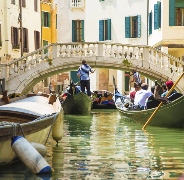VENICE, ITALY - June 19, 2014:  gondoliers in a gondolas passing under a bridge on a small canal, during the Carnival in Venice.  - Foto, Bild