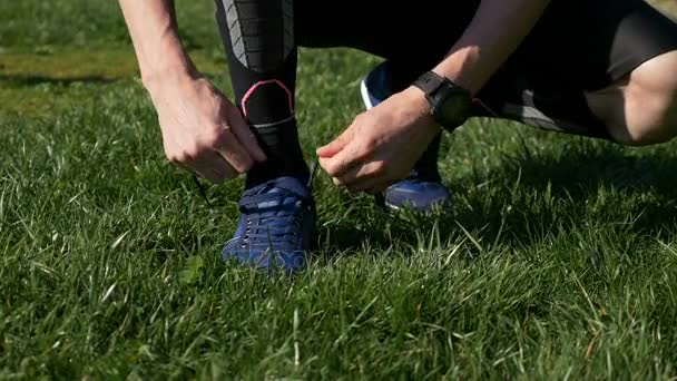 Closeup of athlete man tying shoelaces before jogging in the park - Felvétel, videó