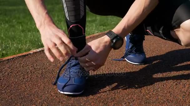 Fit jogger tying both shoelaces before running practice on track race - Filmati, video