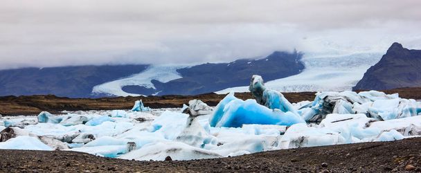 Потрясающий вид на зимний день Йоколсарлон, ледниковую речную лагуну, большое ледниковое озеро, юго-восточная Исландия, на краю национального парка Ватнайкулл, одно из природных чудес Исландии. Большой светящийся голубой айсберг напоминает призрачного рыцаря верхом на лошади
 - Фото, изображение