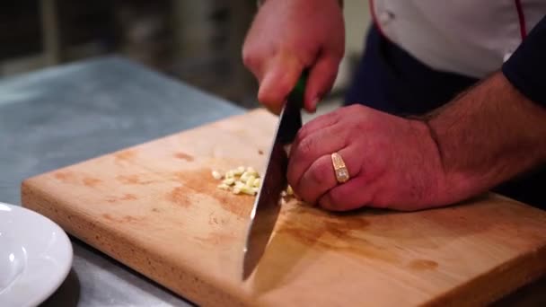 Um chef cortando alho em uma tábua de corte. Um homem a cortar comida. Homem cortando o alho com faca
 - Filmagem, Vídeo