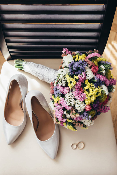 Wedding rings next to the bride's shoes and wedding bouquet - Foto, Imagem