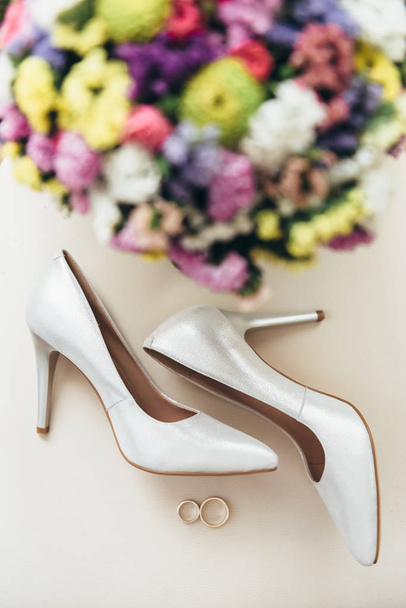Snubní prsteny vedle obuvi a svatební kytice nevěsty - Fotografie, Obrázek