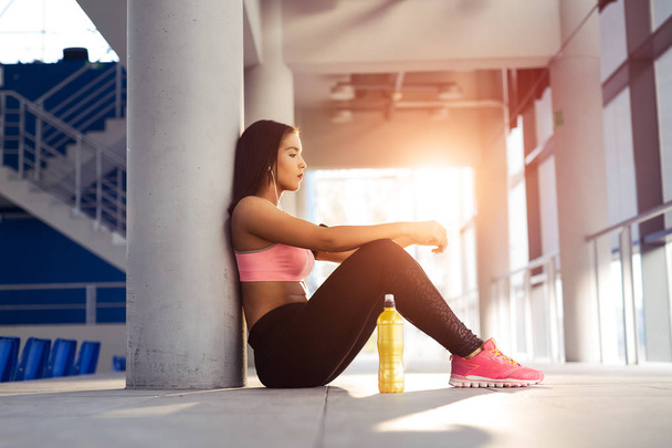 Young woman with earphones listening to music after hard workout - 写真・画像