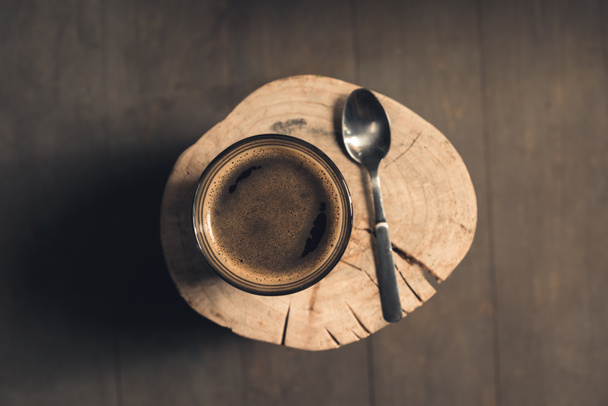 Glass of coffee and spoon on wood - Фото, зображення