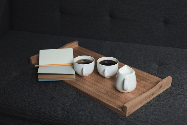 coffee, jug of milk and notebook on tray - Φωτογραφία, εικόνα