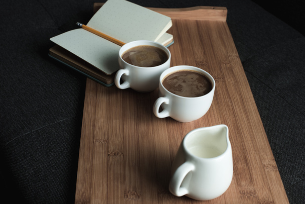 café, jarra de leche y cuaderno en bandeja
 - Foto, Imagen