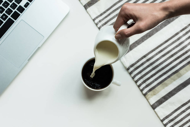 pouring milk into cup of black coffee  - Фото, зображення