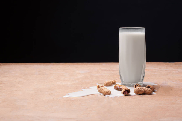 spilled milk with peanuts on wooden background; - Foto, imagen
