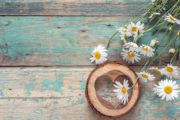 Bouquet of daisies with wooden heart on old wooden background. P - 写真・画像