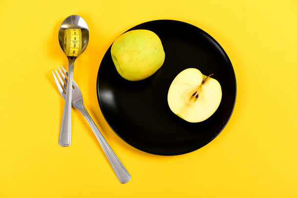 Juicy green apple lying on plate with spoon and fork - Fotó, kép
