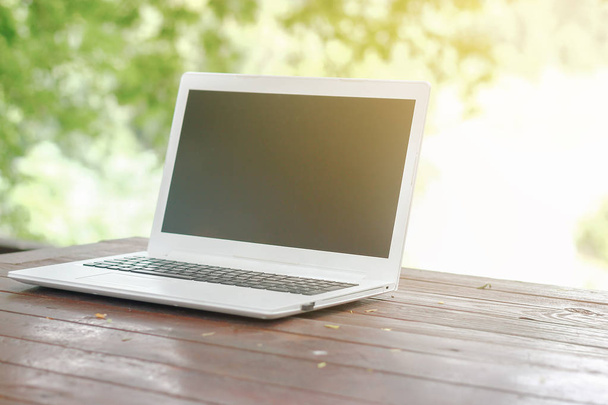 Varastossa kuva Tietokone kannettava tietokone tyhjä takaisin näytön puinen pöytä vihreä puutarha luonto tausta
 - Valokuva, kuva