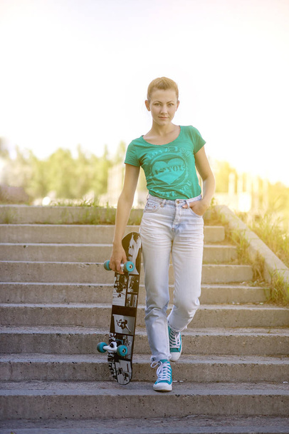 Beautiful beautiful girl rides on highway on Longboard scenic street. Solar toning. A close-up portrait - Foto, afbeelding