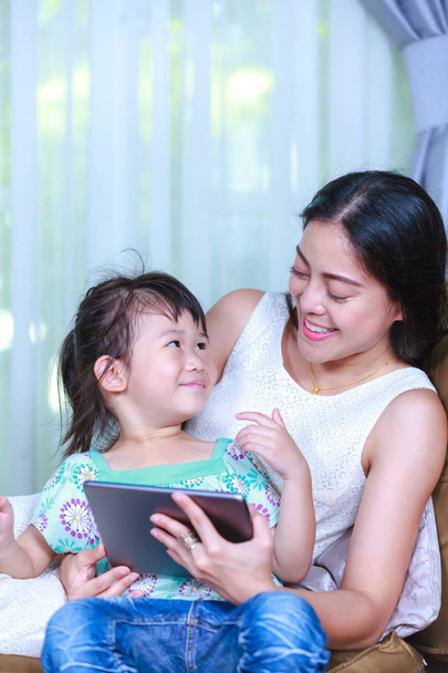 Mother and daughter using digital tablet. Family spending time together at home. - Fotó, kép