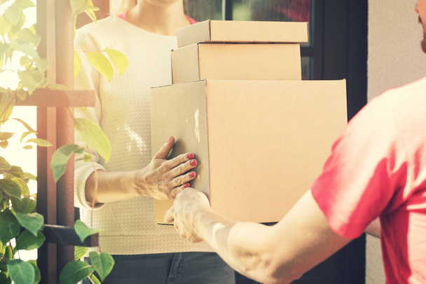 vrouw accepteren een thuisbezorging van dozen van levering dienst courier - Foto, afbeelding
