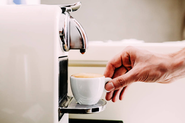 Close up of hand of a barista making coffee using a coffee machine. Mans hand with a cup of fresh coffee with foam - Foto, Imagen