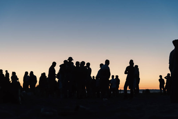 Mucha gente en silueta afuera al atardecer cielo puesta de sol. - Foto, Imagen
