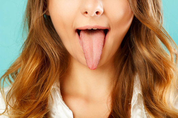 close up of healthy woman tongue over blue background - 写真・画像