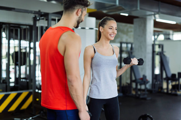 Young adult woman working out in gym with trainer - Foto, Imagem