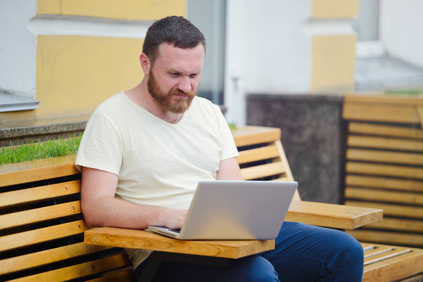 Бизнес и свобода. Человек с бородой за ноутбуком в городе, свободный стиль, современный бизнес
. - Фото, изображение