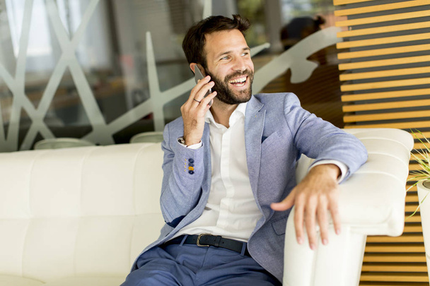 Young businessman using phone in office - Foto, imagen