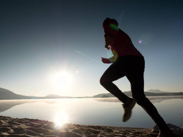 Magas alkalmas ember fut gyorsan a tenger mellett, a tengerparton. Erős futó képzés szabadtéri nyári reggel. - Fotó, kép