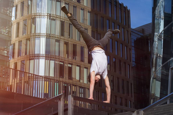Young man doing handstand in the city - Фото, изображение