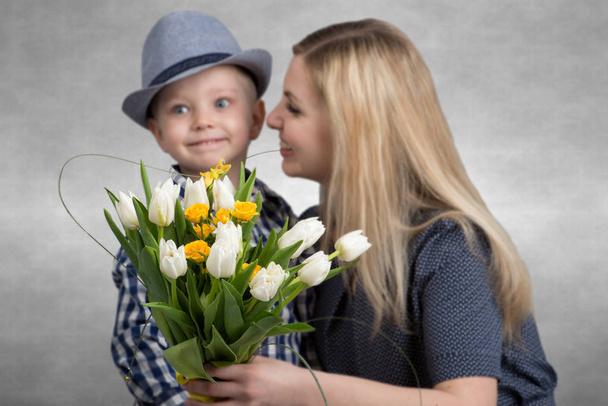 Small son gives his beloved mother a bouquet of beautiful tulips. Spring, concept of family vacation. Bouquet of flowers closeup. - Fotografie, Obrázek
