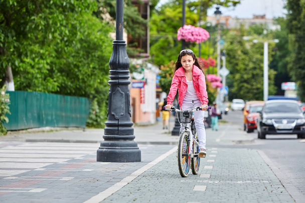 Cute kid in safety helmet biking outdoors. Little girl on a red bicycle Healthy preschool children summer activity. - 写真・画像