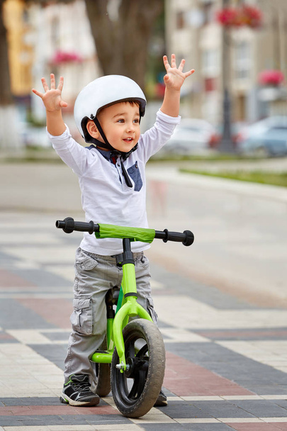 Little boy kid in helmet ride a bike in city park. Cheerful child outdoor. - Photo, Image