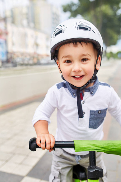 Little boy kid in helmet ride a bike in city park. Cheerful child outdoor. - Фото, зображення